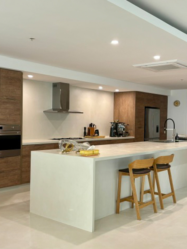 Open-plan kitchen with a white waterfall island bench and timber bar stools